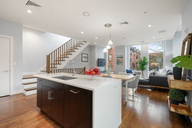 a view of a living room and kitchen with furniture wooden floor and windows