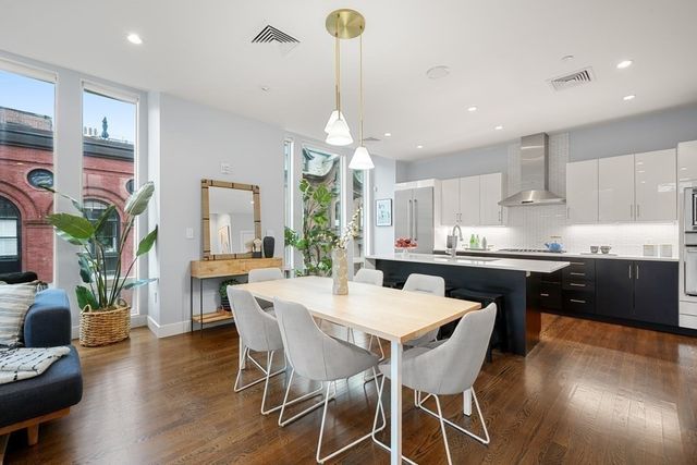 a kitchen with stainless steel appliances granite countertop a dining table chairs stove a refrigerator and cabinets