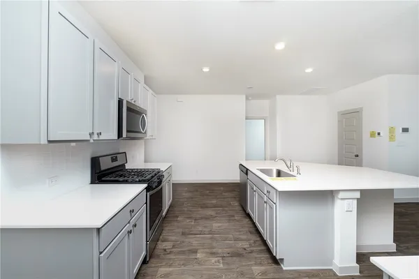 a kitchen with stainless steel appliances a sink a stove top oven a counter space and cabinets