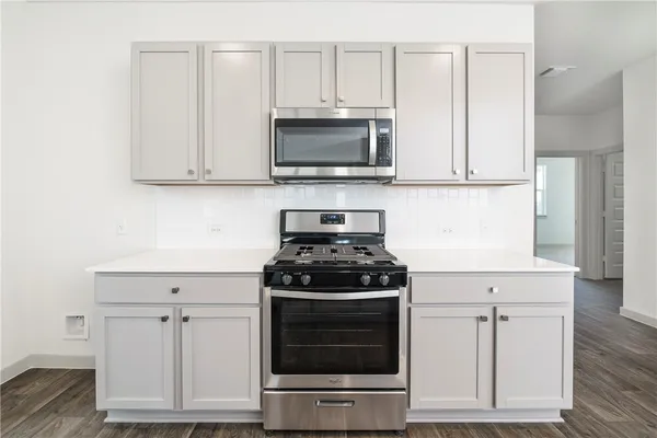 a kitchen with stainless steel appliances granite countertop white cabinets and a stove a oven with white countertops