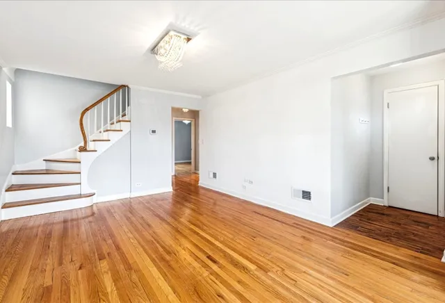 a view of an empty room with wooden floor and a ceiling fan