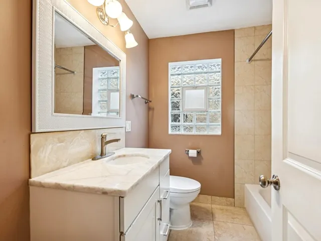 a bathroom with a granite countertop sink mirror and a toilet