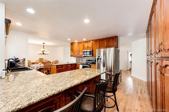 a kitchen with granite countertop a table chairs refrigerator and sink