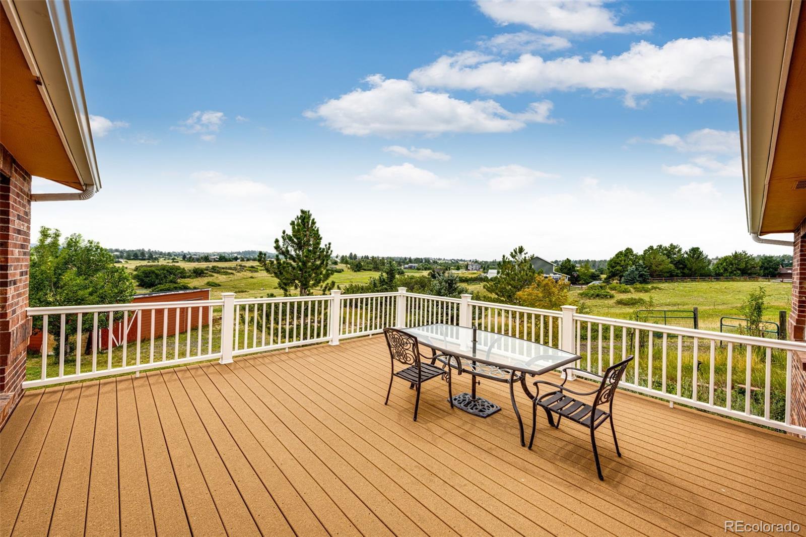 2218 Deerpath Road Franktown, CO 80116 - Photo 17 of 46 a balcony with wooden floor table and chairs