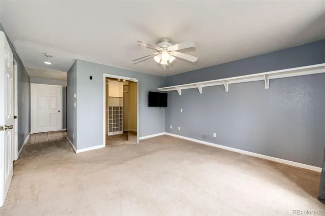 an empty room with closet and a ceiling fan