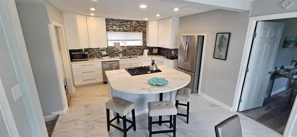 a kitchen with stainless steel appliances a refrigerator a stove a sink and white cabinets with wooden floor