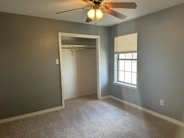 an empty room with windows and chandelier fan