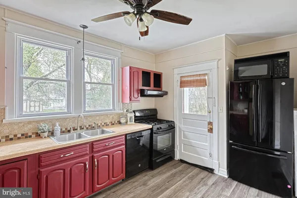 a kitchen with granite countertop stainless steel appliances a sink cabinets and wooden floor