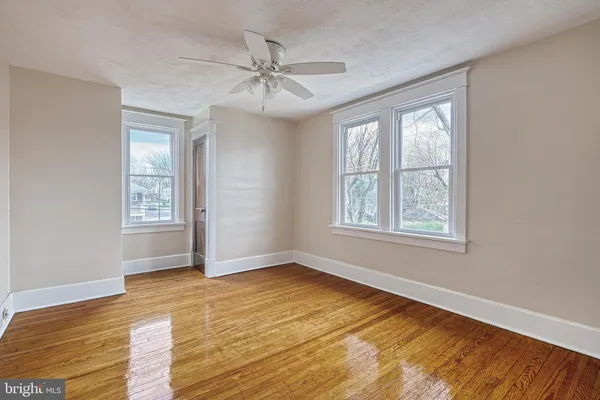 a view of empty room with wooden floor and fan