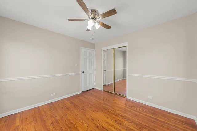 an empty room with wooden floor and ceiling fan