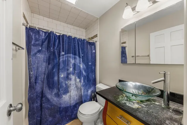 a bathroom with a granite countertop sink toilet a mirror and shower
