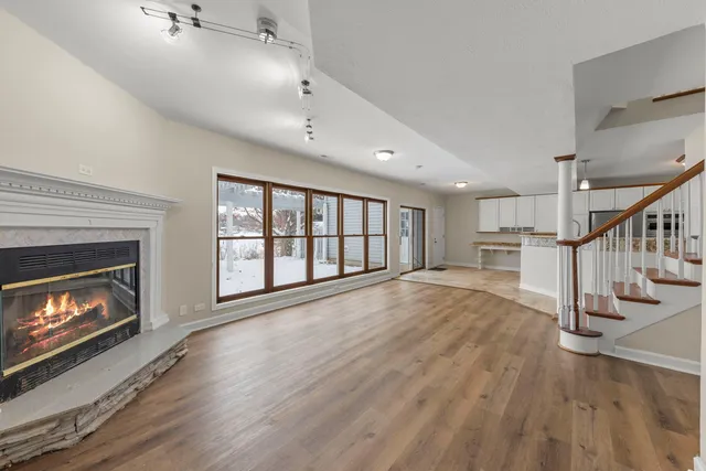 a view of an empty room with wooden floor fireplace and a window