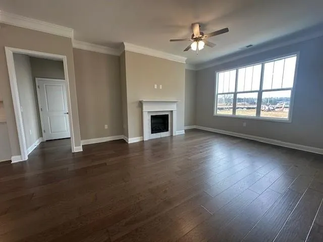 an empty room with wooden floor fireplace and windows