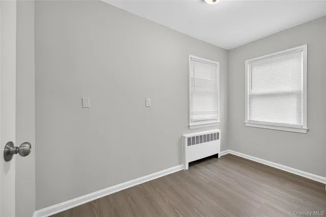 an empty room with wooden floor cabinet and windows