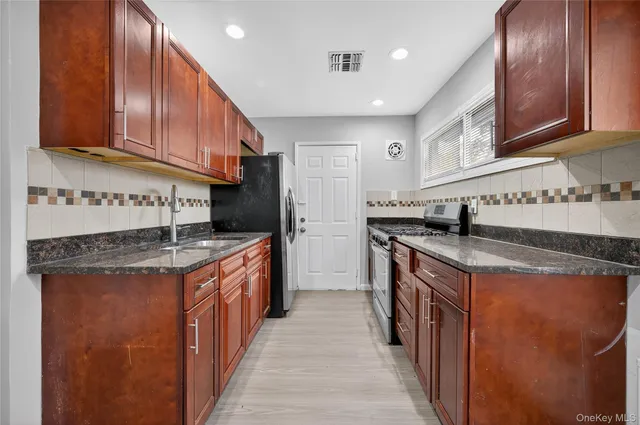 a kitchen with stainless steel appliances granite countertop a stove top oven a sink dishwasher and cabinets with wooden floor