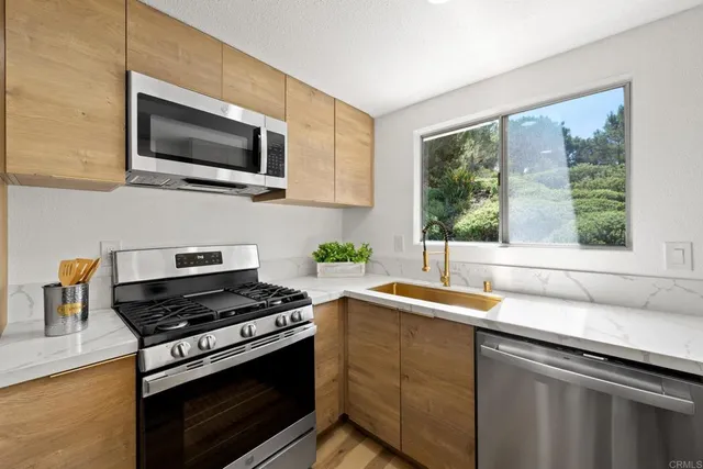 a kitchen with stainless steel appliances a stove a sink and a microwave