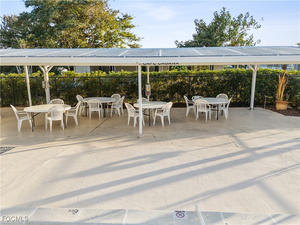 455 Cape Florida Way Naples, FL 34104 - Photo 16 of 35 a view of a patio with table and chairs potted plants and large trees