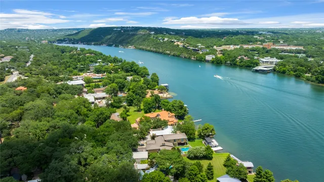 an aerial view of a house with swimming pool a yard and lake view