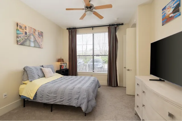 a bedroom with a bed and a flat tv screen on dresser