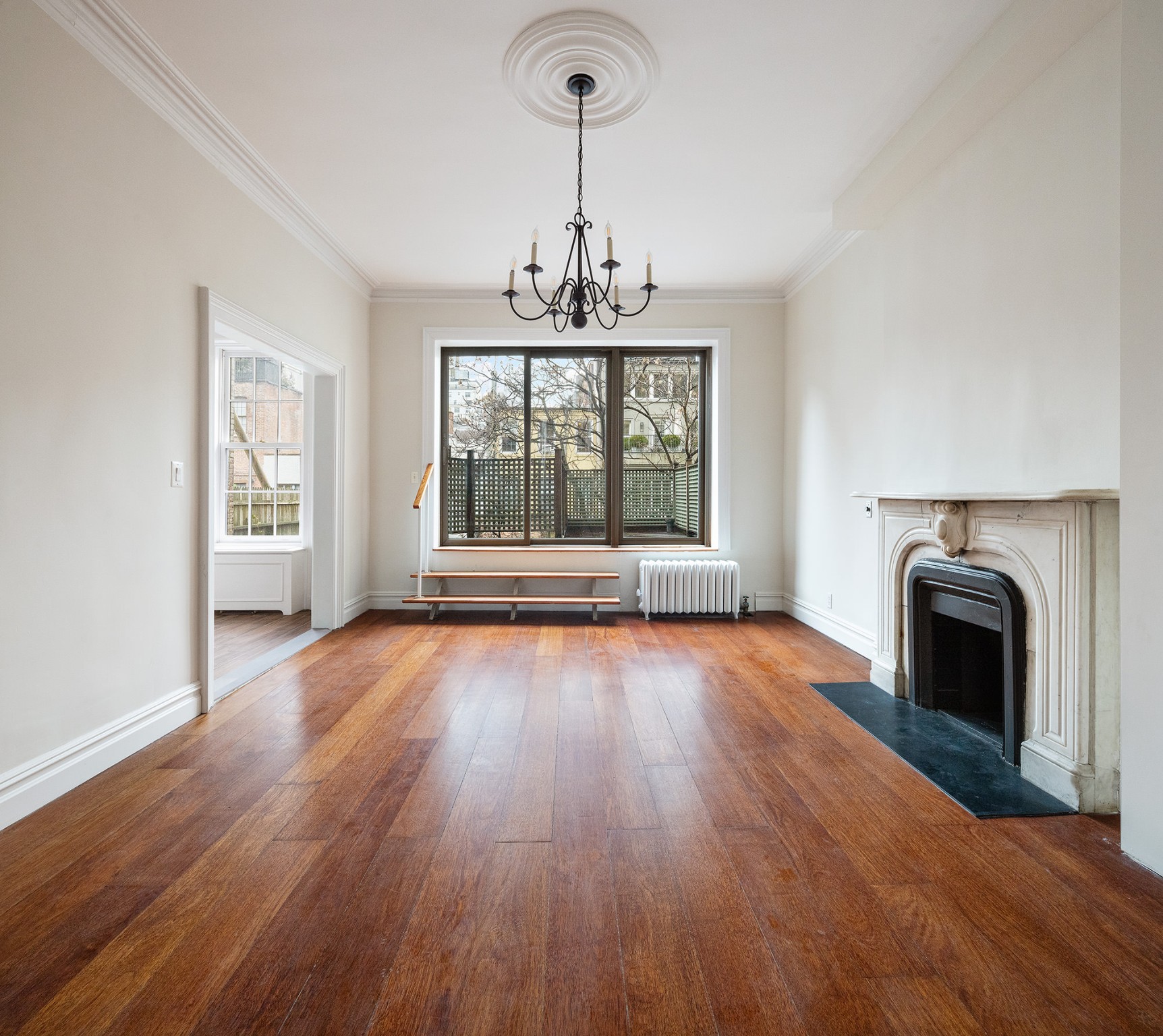 127 East 69th Street, Unit 4 Manhattan, NY 10021 - Photo 4 of 17 an empty room with wooden floor windows and fireplace