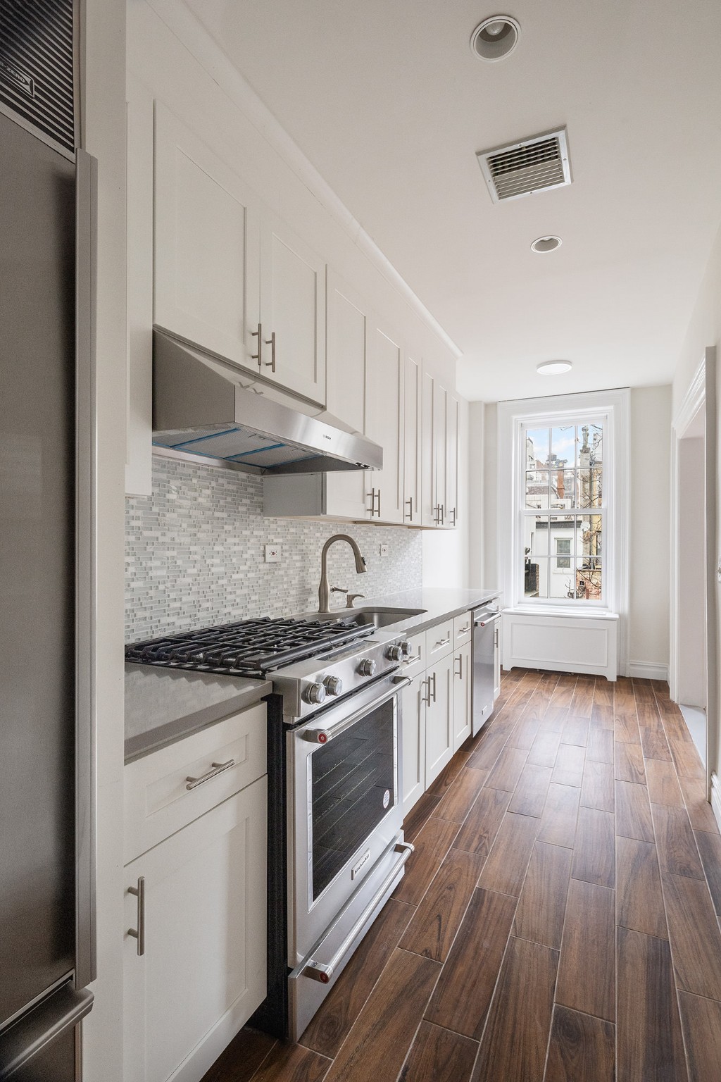 127 East 69th Street, Unit 4 Manhattan, NY 10021 - Photo 5 of 17 a kitchen with stainless steel appliances granite countertop hardwood floor sink stove and cabinets