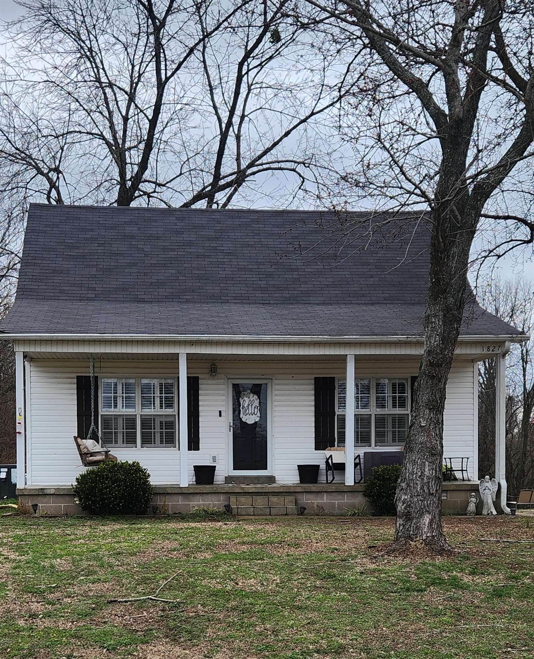 View of front of house featuring covered porch, a shingled roof, and a front lawn