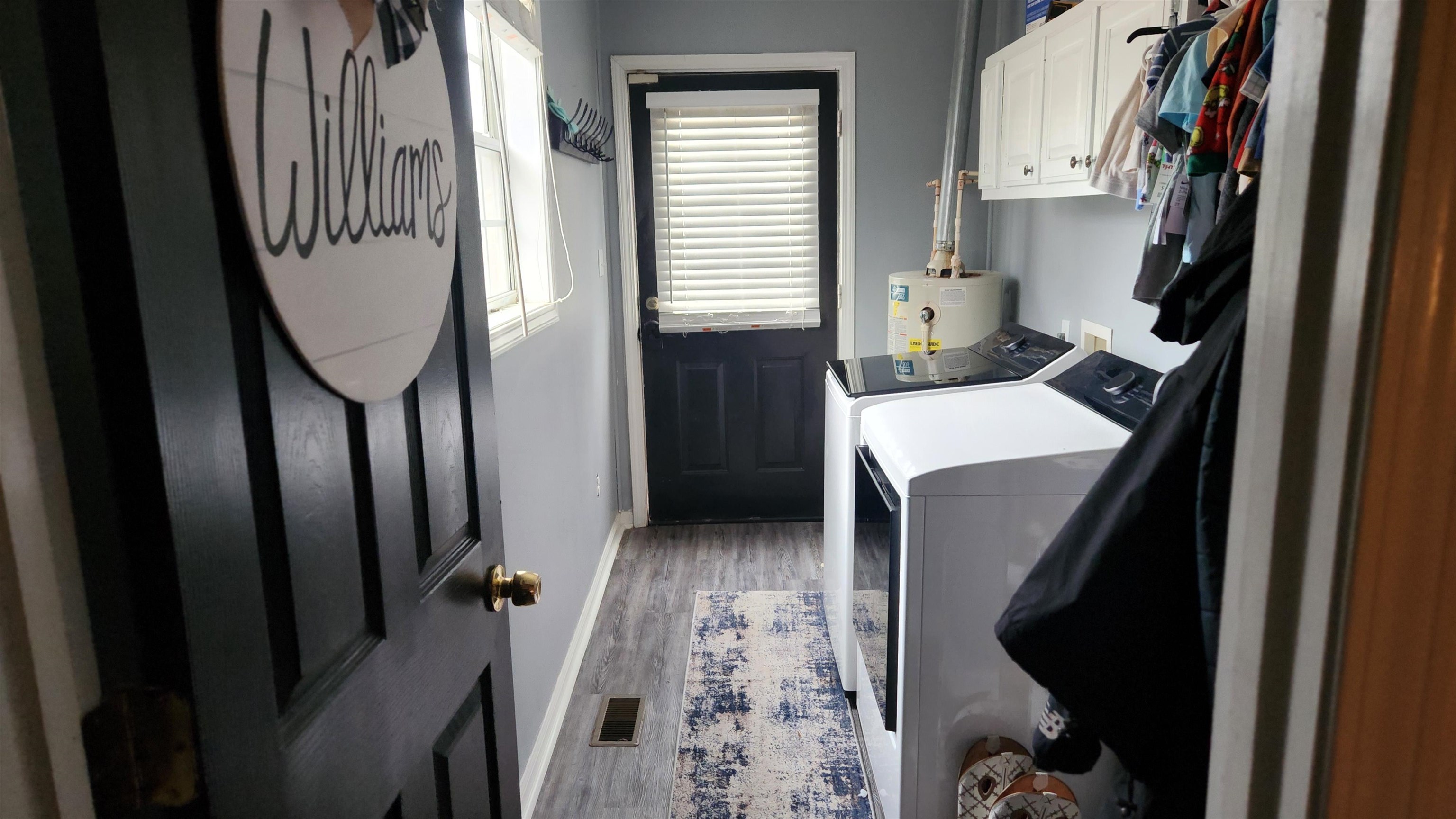 1827 Arp Central Road Ripley, TN 38063 - Photo 7 of 18 Laundry room featuring cabinet space, light wood-style floors, washer and dryer, and water heater