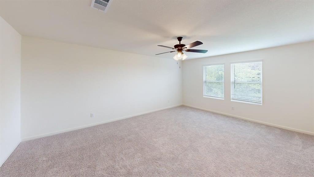 4529 Winecup Road Melissa, TX 75454 - Photo 9 of 29 Spacious room with neutral-toned carpeting, light-colored walls, dual windows with blinds, an overhead ceiling fan with lighting, and a visible air vent
