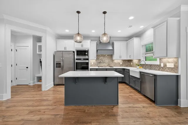 a kitchen with stainless steel appliances granite countertop a sink a stove and a wooden floors