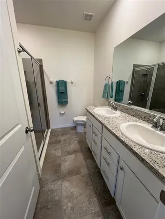 a bathroom with a granite countertop sink a mirror and a toilet