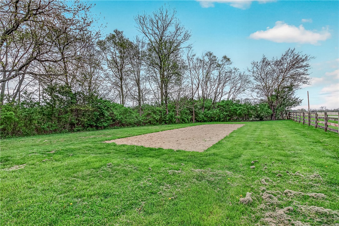 8700 Quaker Trace Road Camden, OH 45311 - Photo 26 of 34 Expansive green yard with a dedicated garden space and a rustic fence border.