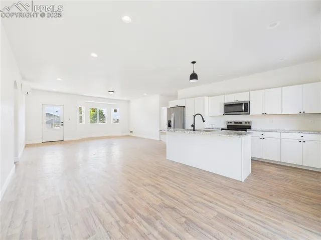 a view of kitchen with cabinets stainless steel appliances and wooden floor