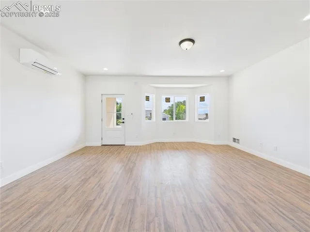 an empty room with wooden floor and windows