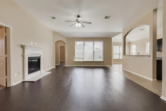 an empty room with wooden floor chandelier and fireplace