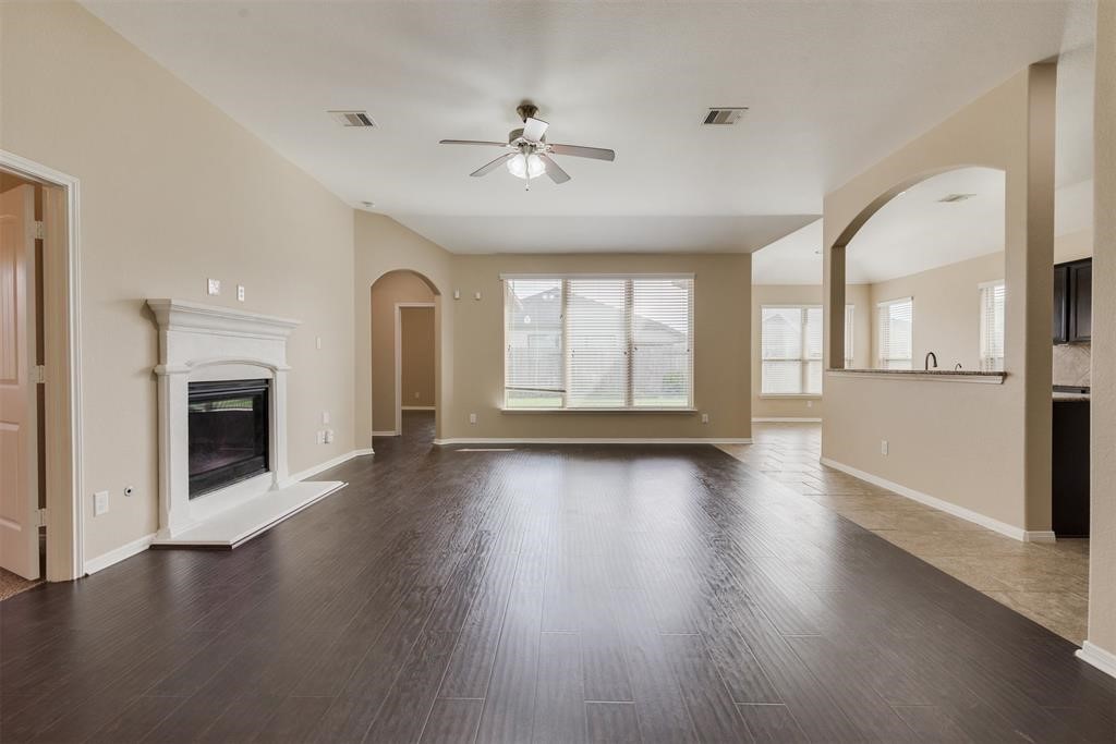 1903 Cadbury Castle Lane Fresno, TX 77545 - Photo 10 of 14 an empty room with wooden floor chandelier and fireplace