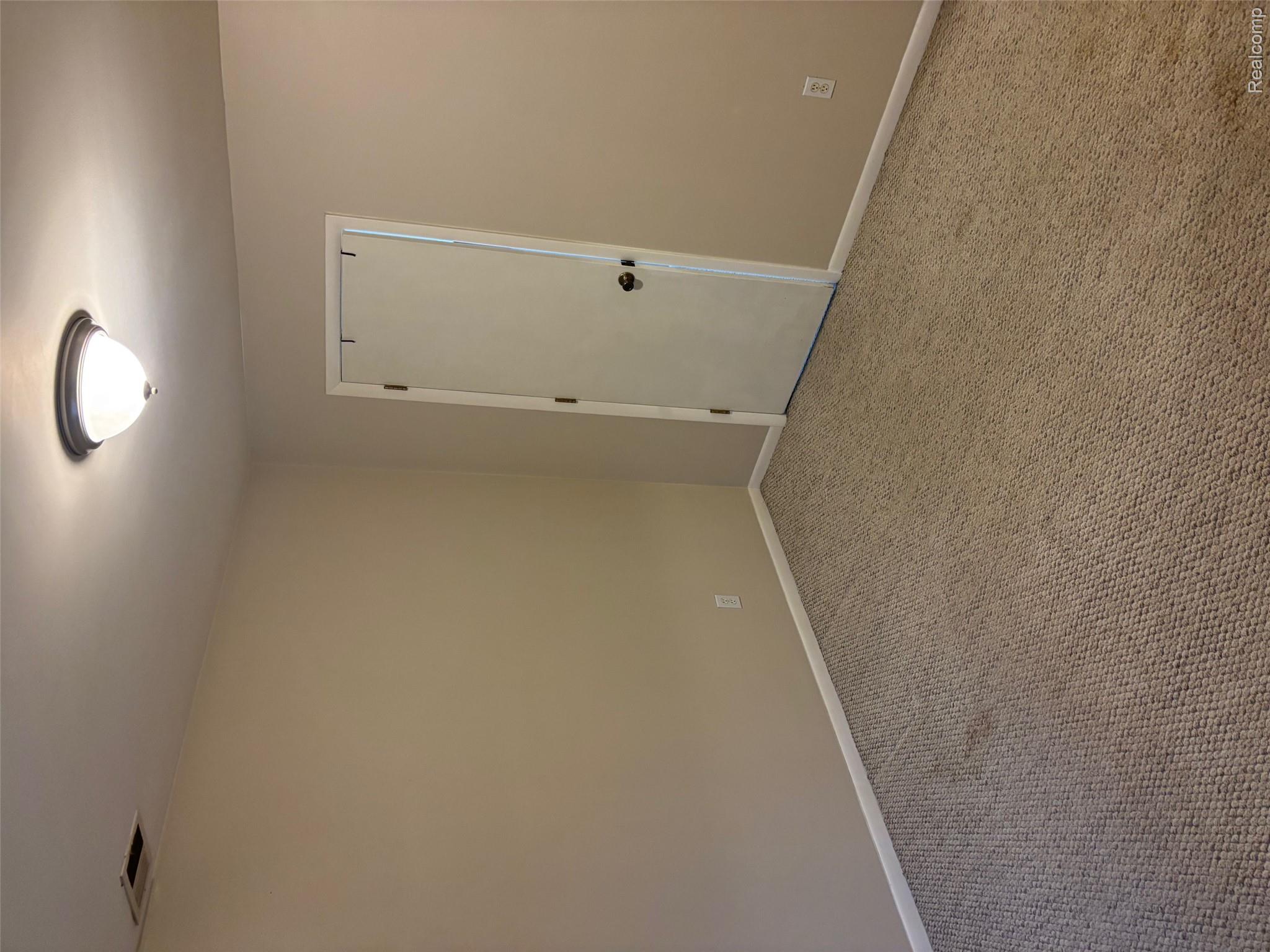 Wall-to-wall carpeting with neutral wall tones and a ceiling-mounted light fixture