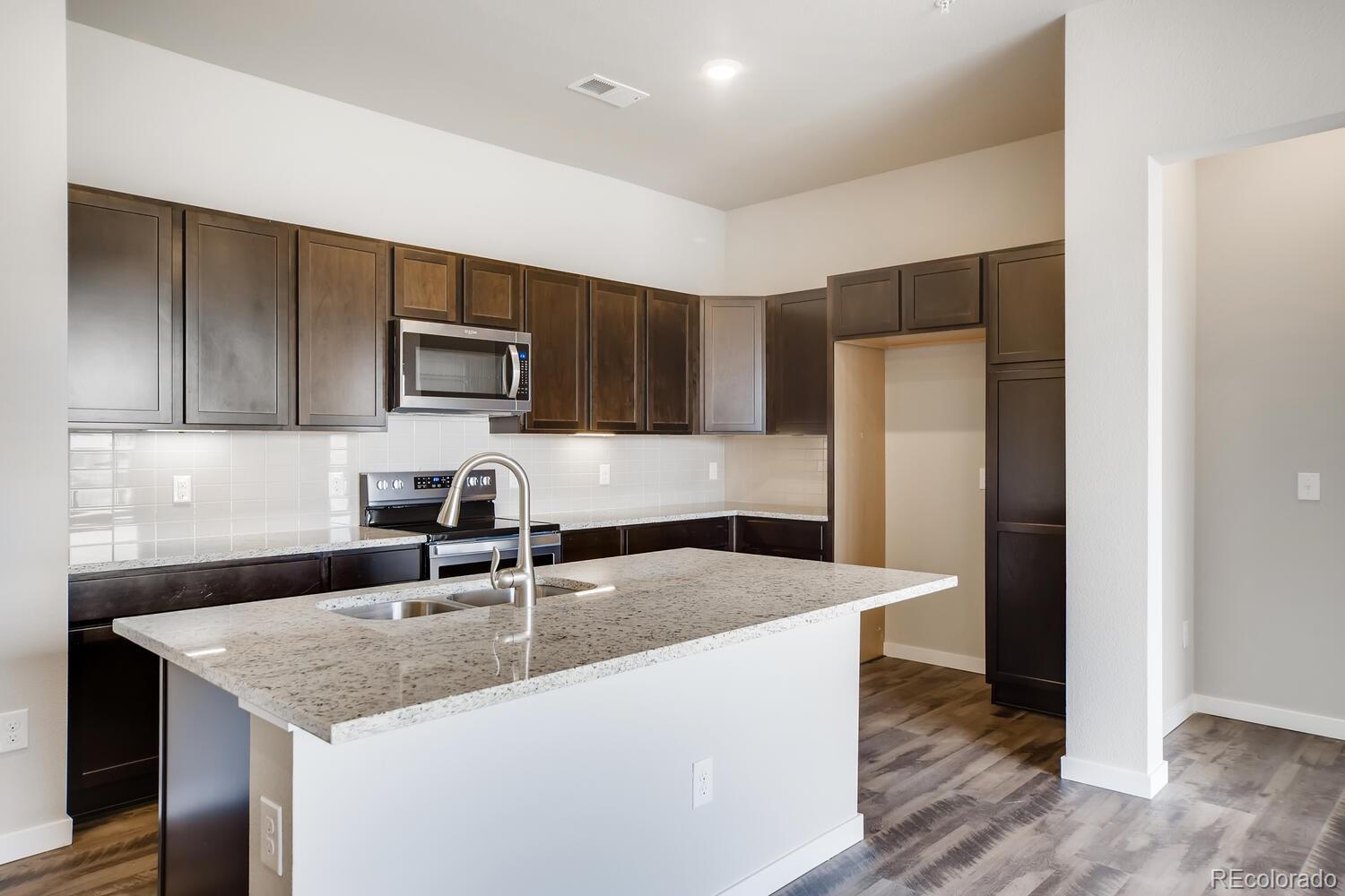 9283 Twenty Mile Road, Unit 406 Parker, CO 80134 - Photo 3 of 13 a kitchen with kitchen island granite countertop a sink and refrigerator