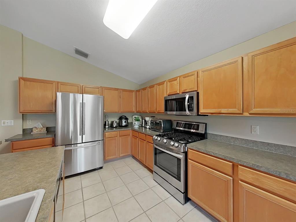30612 Nickerson Loop Wesley Chapel, FL 33543 - Photo 18 of 47 a kitchen with stainless steel appliances granite countertop a refrigerator stove top oven and sink
