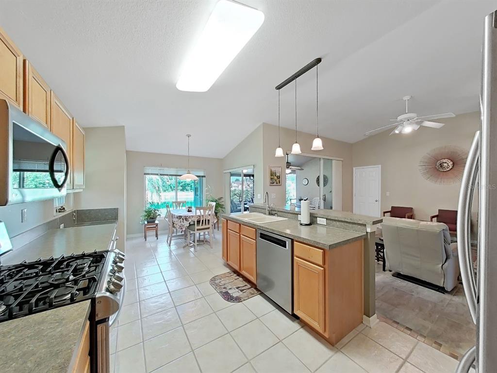 30612 Nickerson Loop Wesley Chapel, FL 33543 - Photo 19 of 47 a kitchen with stainless steel appliances granite countertop a stove and a view of living room