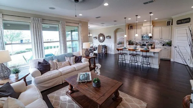 a living room with furniture a large window and wooden floor