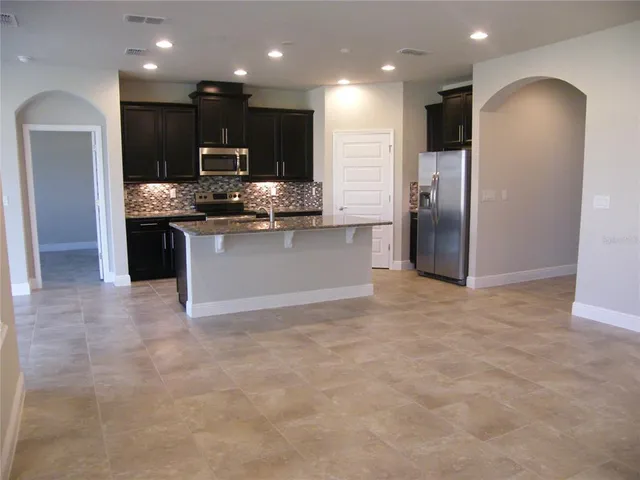 a kitchen with granite countertop a stove refrigerator and microwave