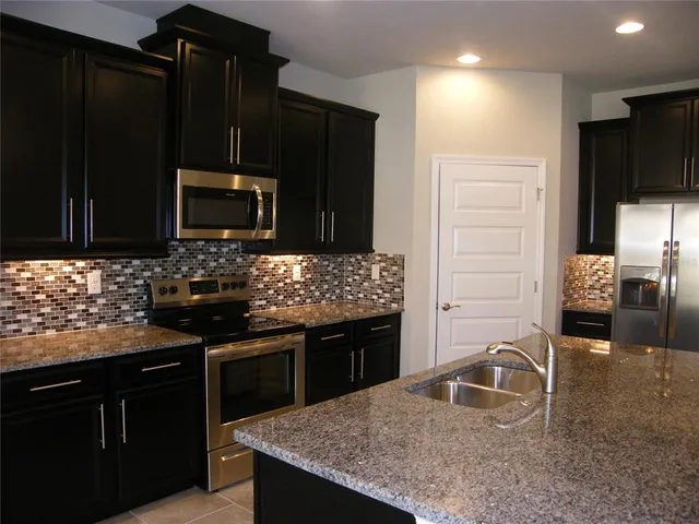 a kitchen with granite countertop stainless steel appliances a stove microwave and sink