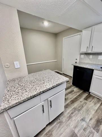 a view of kitchen with granite countertop white cabinets and a sink
