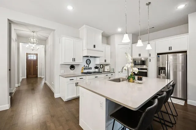 a kitchen with stainless steel appliances kitchen island a table chairs refrigerator and microwave