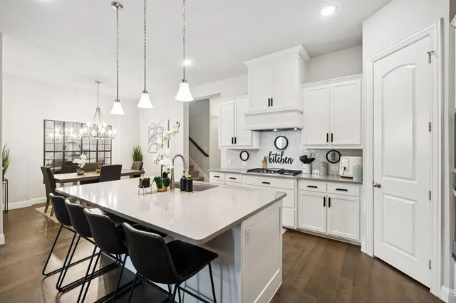 a kitchen with stainless steel appliances a table chairs and white cabinets