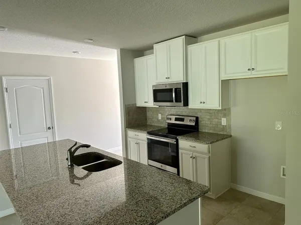 a kitchen with stainless steel appliances granite countertop a sink stove and microwave