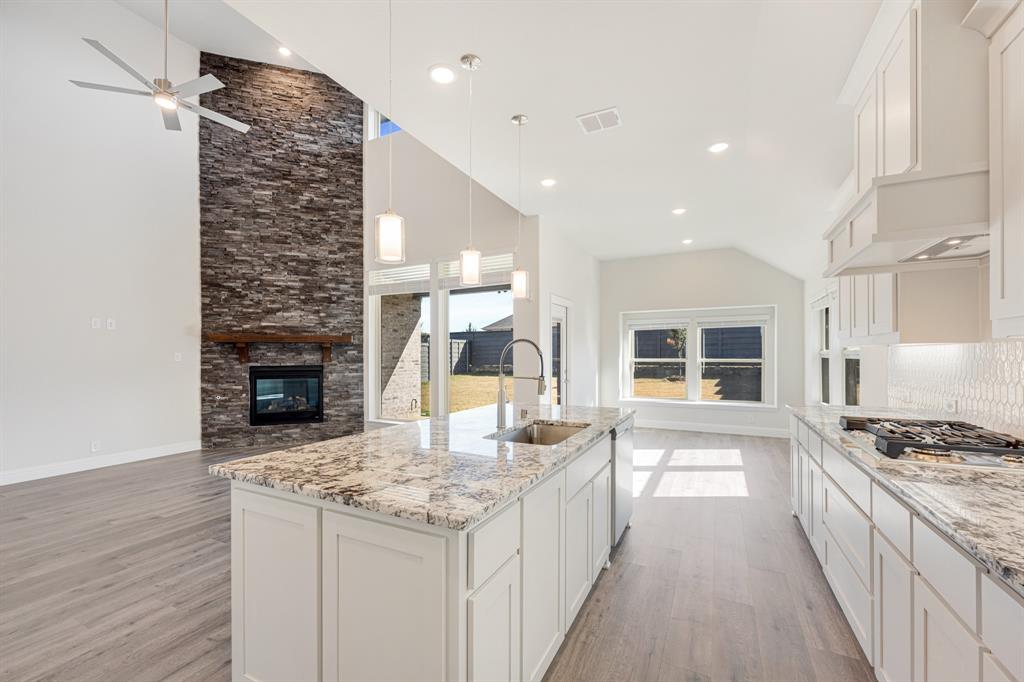 7316 Iris Road Aubrey, TX 76227 - Photo 14 of 40 a kitchen with kitchen island granite countertop a stove and a wooden floors