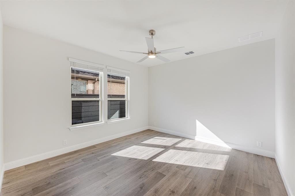 7316 Iris Road Aubrey, TX 76227 - Photo 15 of 40 an empty room with wooden floor fan and windows