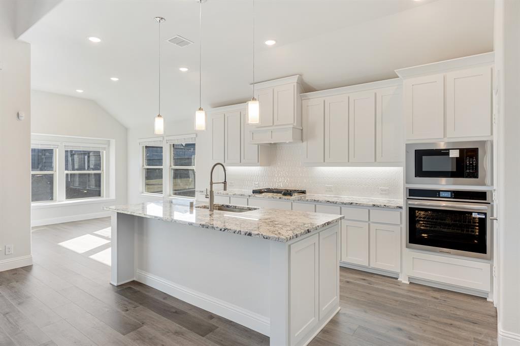 7316 Iris Road Aubrey, TX 76227 - Photo 9 of 40 a kitchen with stainless steel appliances granite countertop a sink and a stove