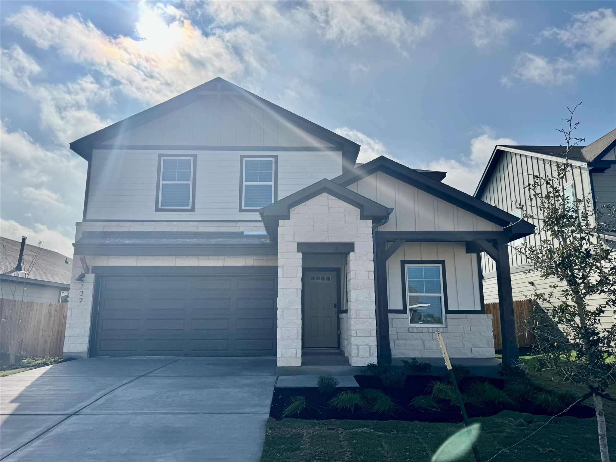 Craftsman-style house featuring stone siding, concrete driveway, board and batten siding, and a garage